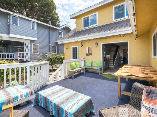 A yellow house with a white fence and a blue and white striped blanket on the patio.