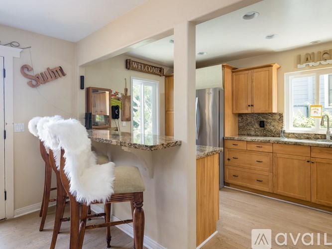 A kitchen with a bar stool and a chair with a white furry seat cushion.