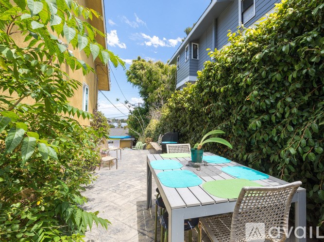 A patio with a table and chairs surrounded by greenery.