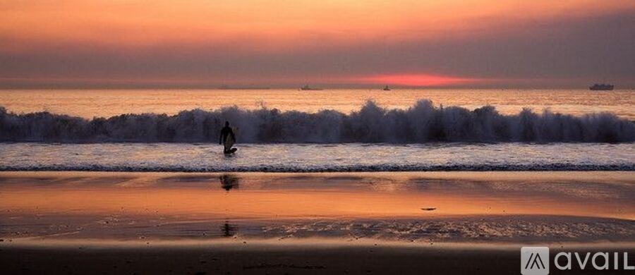 A person is surfing on a wave at sunset.