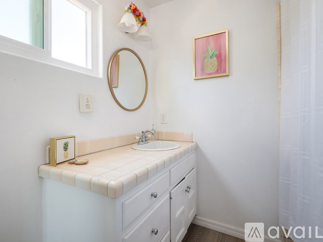 A bathroom with a white sink and a pineapple picture on the wall.