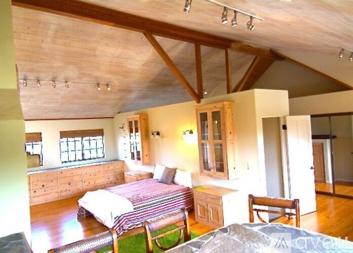 A bedroom with a bed, dresser, and chair.