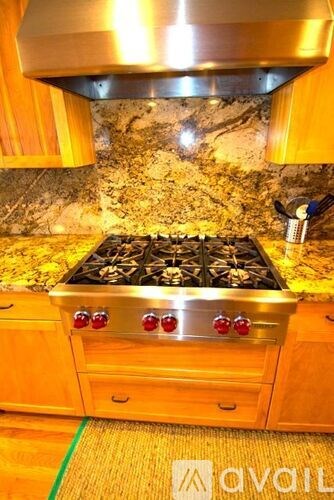 A modern kitchen with a stove top oven and wooden cabinets.