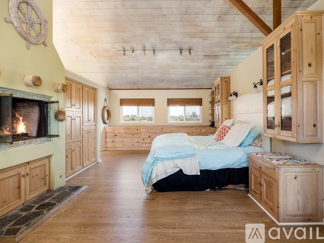 A bedroom with a bed, dresser, and a fireplace.