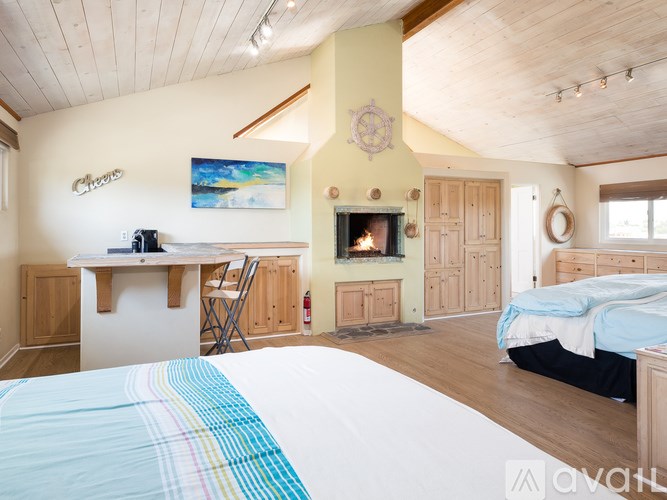 A bedroom with a bed, desk, and fireplace.