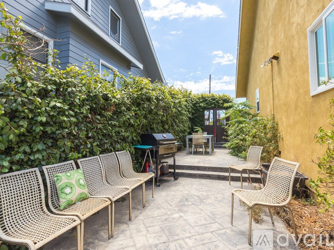 A patio with a table, chairs, and a hedge.