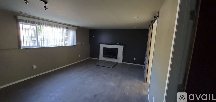 A large empty room with a fireplace and a window.
