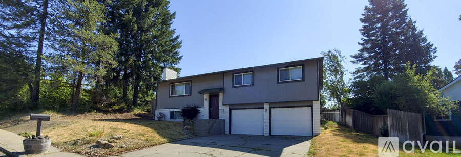 A two-story house with a garage is surrounded by trees and has a driveway leading to the garage.