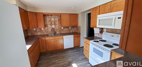 A kitchen with wooden cabinets and a white stove top oven.