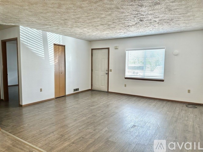 A room with wooden floors and a window with blinds.