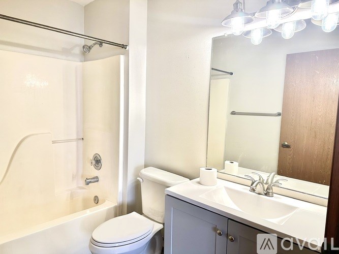 A white toilet is in a bathroom with a white sink and a mirror.