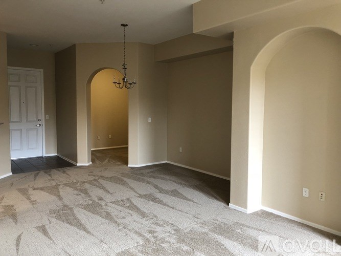 A large empty room with a chandelier and carpeted floor.