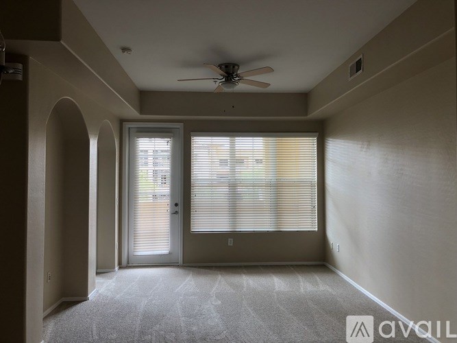 A room with a ceiling fan and a door with blinds.