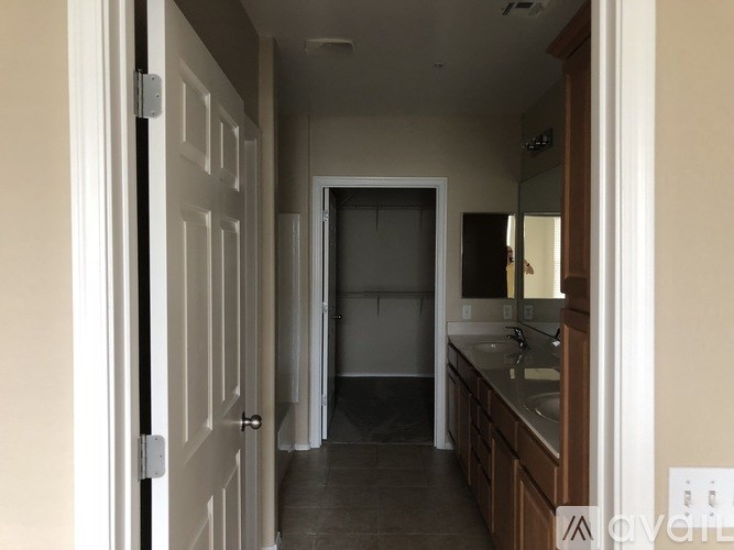 A kitchen with a sink and cabinets is visible through an open door.
