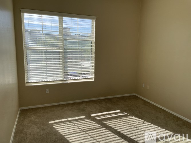A room with a window covered by white blinds.