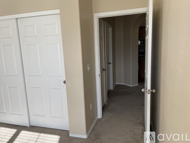 A hallway with a white door on the left and a white door on the right.
