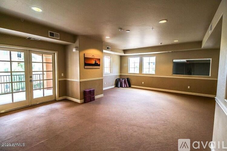 A spacious room with a carpeted floor and a television on the wall.
