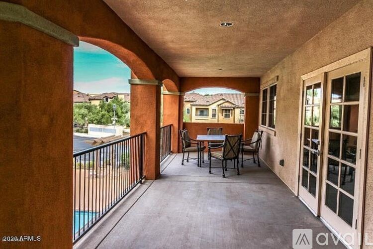 A patio with a table and chairs overlooks a pool.