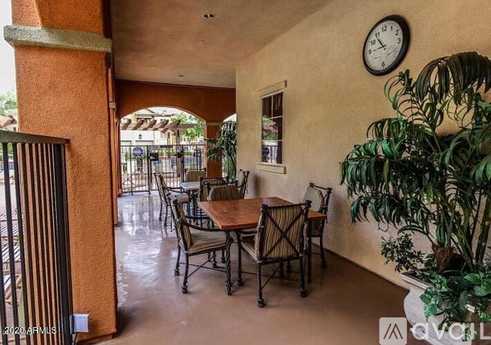 A patio with a table and chairs and a clock on the wall.