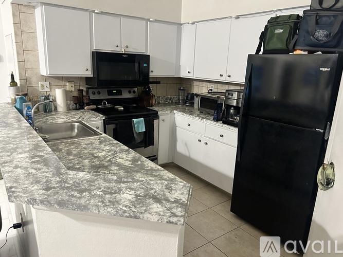 A kitchen with a black fridge and white cabinets.