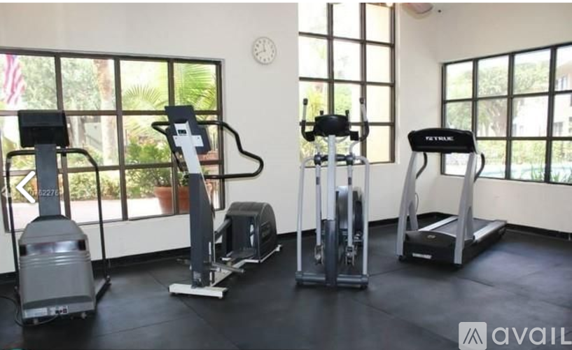 A gym with a row of exercise machines and a clock on the wall.