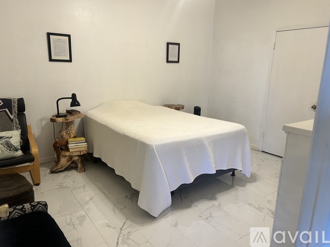 A bedroom with a white bed and a wooden chair.