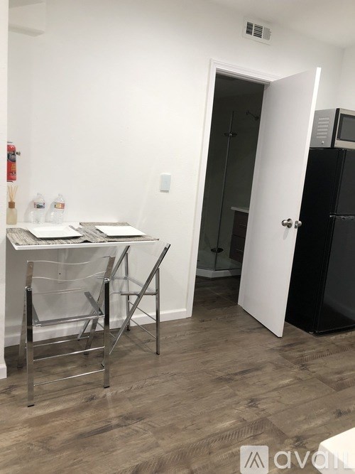 A kitchen with a white table and chairs and a black fridge.