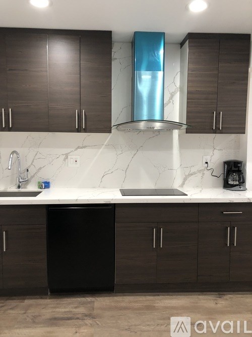 A kitchen with a black dishwasher and a marble countertop.