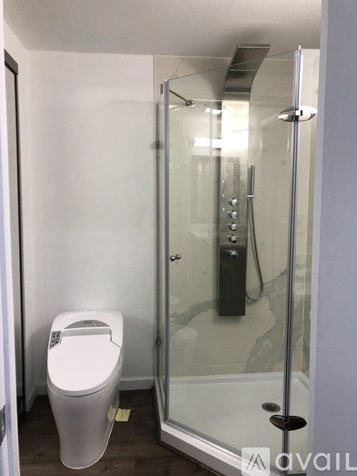 A white toilet is in a small bathroom with a glass shower door.