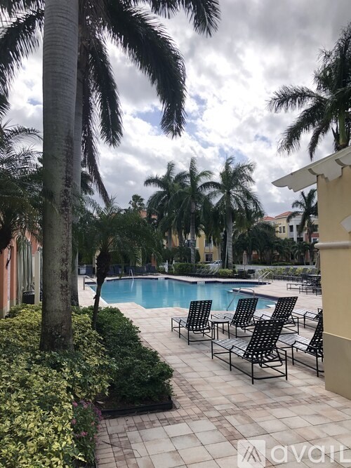 A pool surrounded by palm trees and lounge chairs.