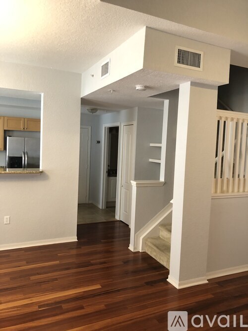 A room with wooden floors and a staircase leading to another room.