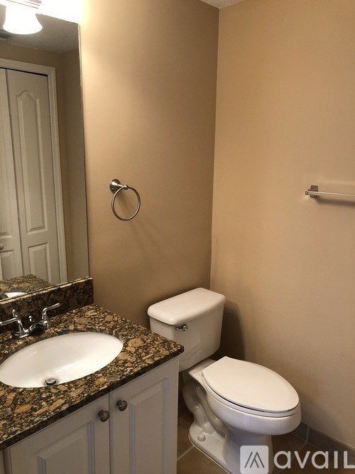 A bathroom with a toilet, sink, and mirror.