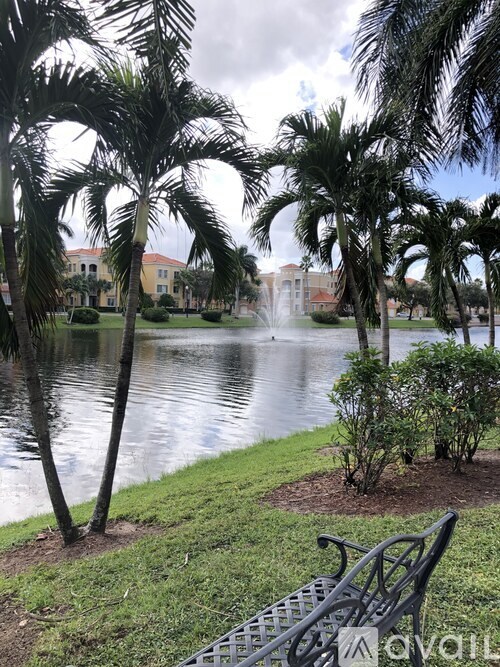 A park with a fountain, bench and trees.