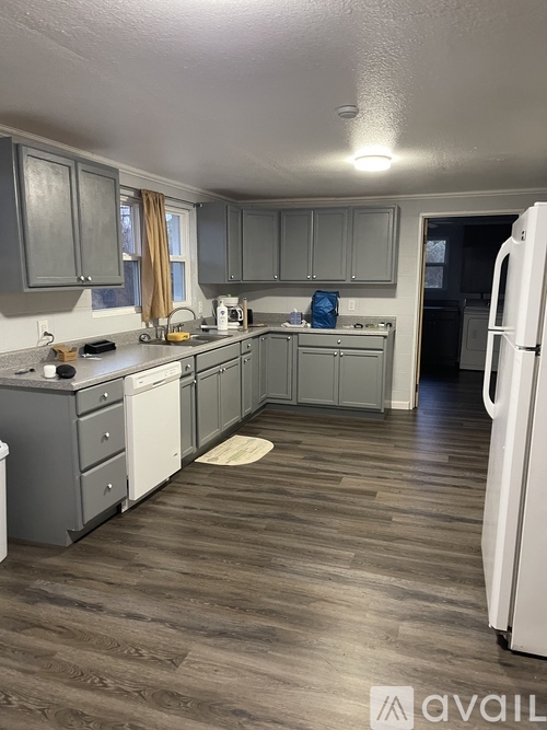 A kitchen with a white fridge and wooden floors.