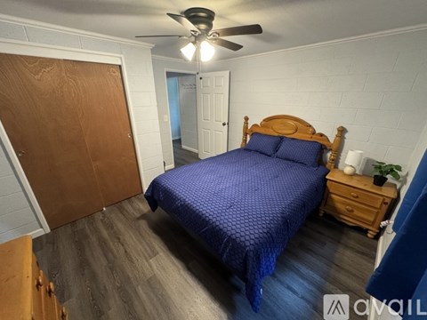 A bedroom with a bed, dresser, and ceiling fan.