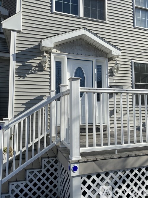 A white wooden deck with a lattice pattern and a small white door.