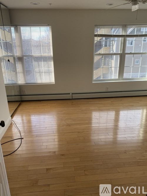 A room with wooden flooring and a window with blinds.
