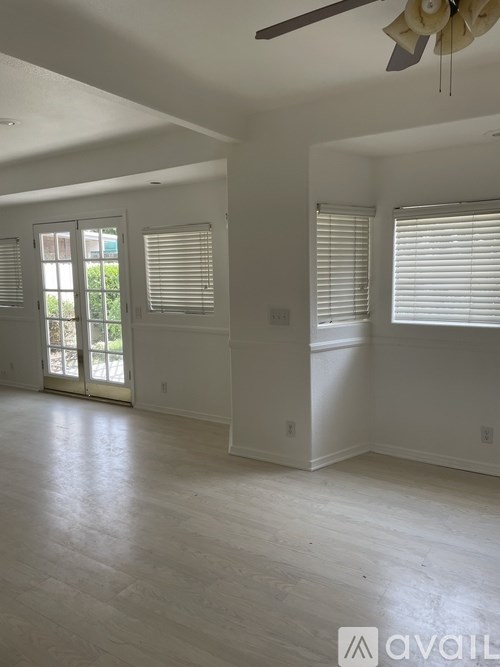 A spacious room with a sliding glass door leading to a balcony.