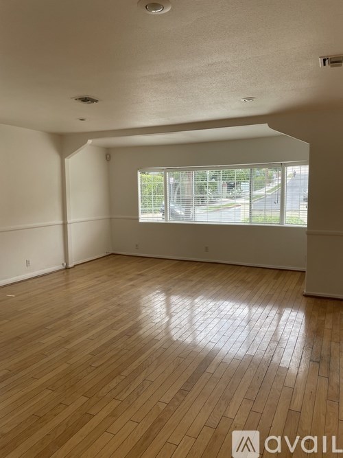 A room with wooden flooring and a window overlooking a street.