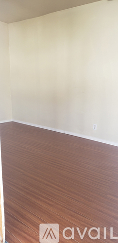 A room with a wooden floor and a white wall.