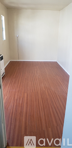 A room with wooden flooring and white walls.