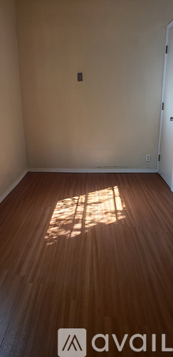 A room with wooden flooring and a wall socket.