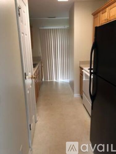 A kitchen with a black fridge and wooden cabinets.