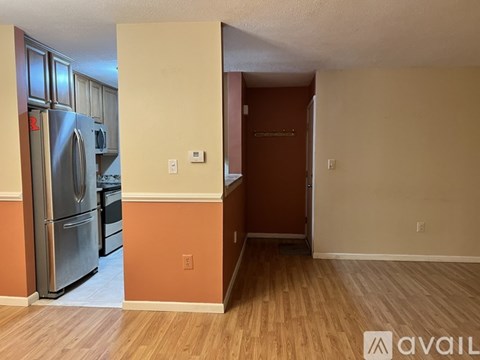 A kitchen with a refrigerator and a wooden floor.