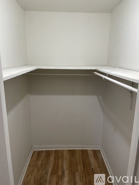 Empty white closet with wood floors.