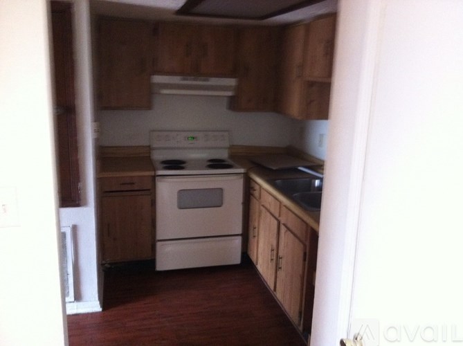 A kitchen with a white stove top oven and wooden cabinets.