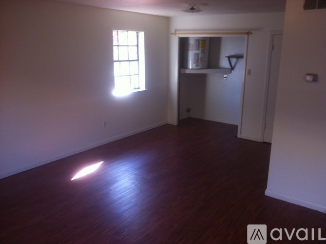 A room with a wooden floor and a window letting in sunlight.