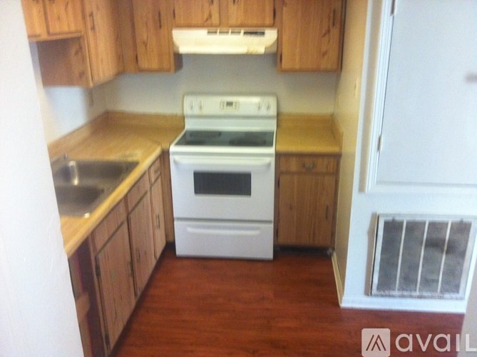 A kitchen with wooden cabinets and a white stove top oven.