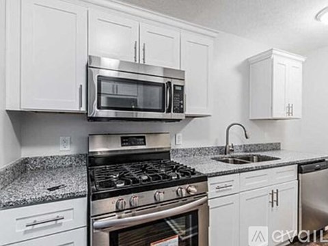 A kitchen with white cabinets and a granite countertop.