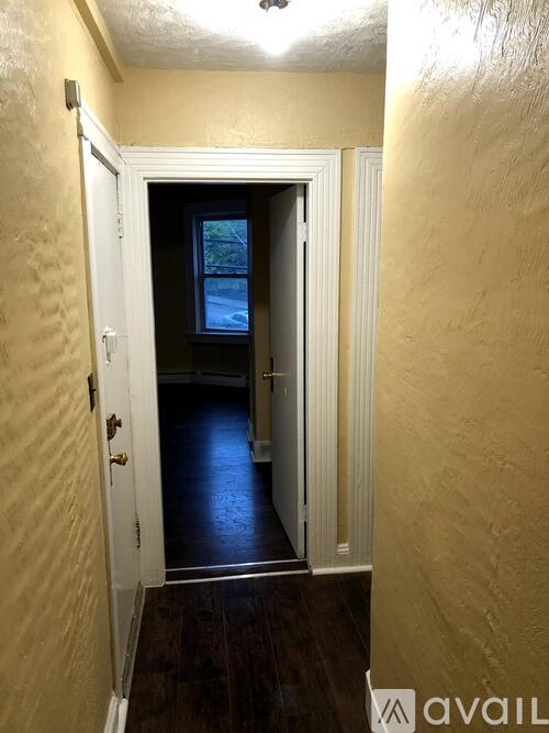A hallway with a door leading to a dark room.